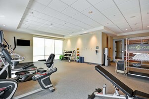 Un gimnasio con cintas de correr, bancos de pesas y mancuernas.