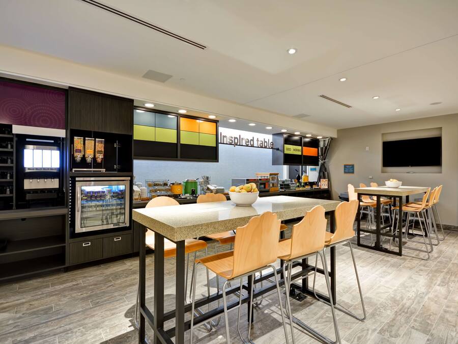 A modern kitchen with a central island, bar stools, and a dining table with chairs.