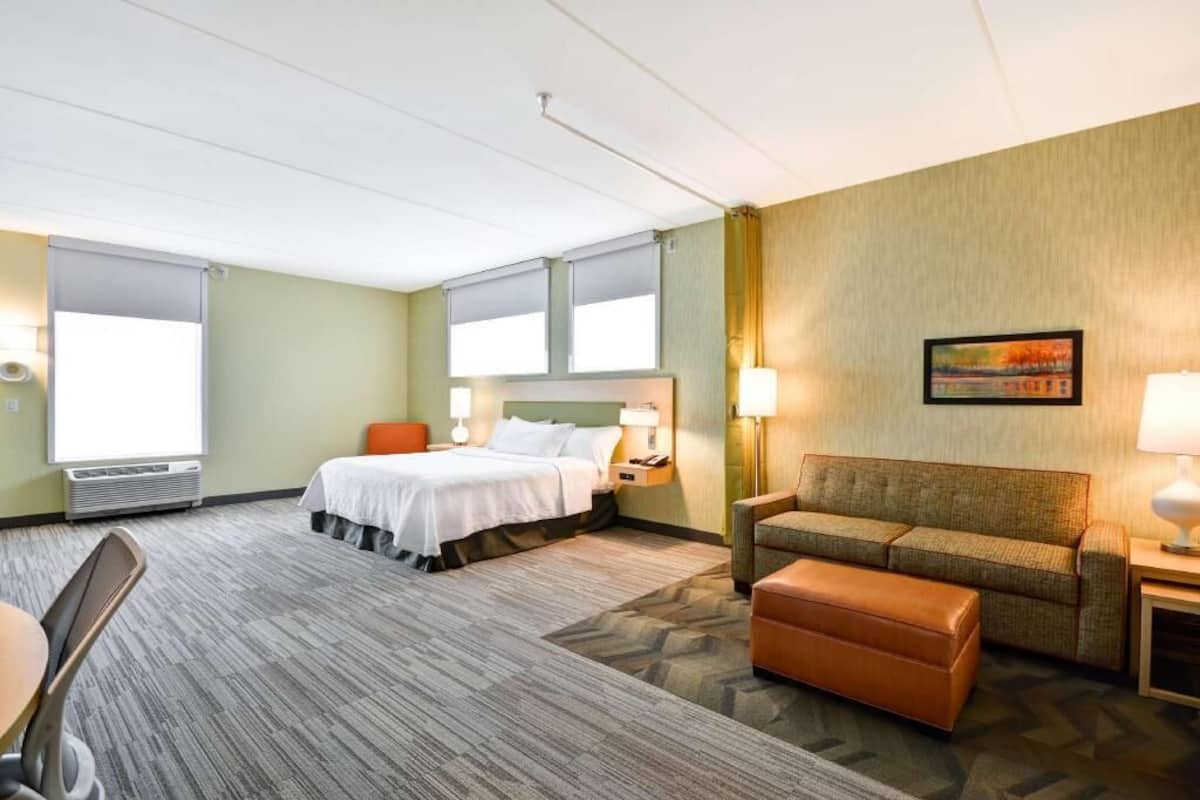 Une chambre d’hôtel avec un lit, un canapé, une table et une chaise.