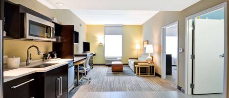 Una habitación de hotel moderna con kitchenette, escritorio, sofá y cama.
