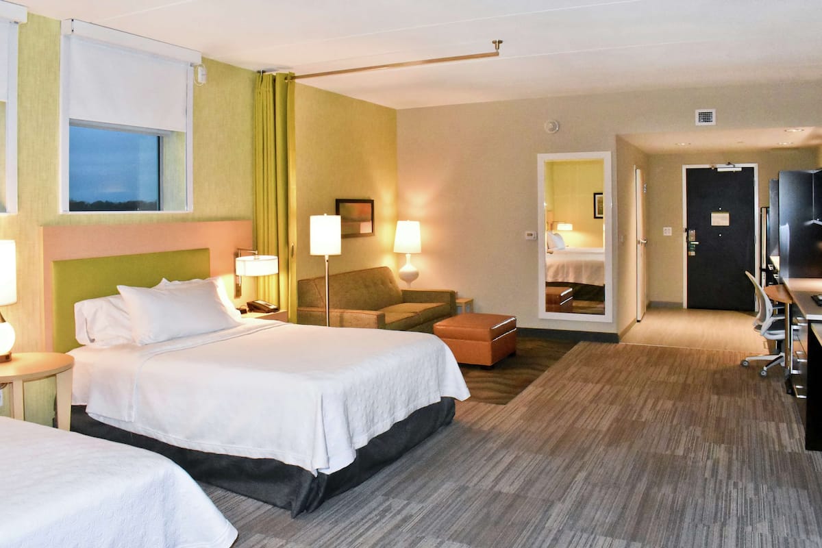 Une chambre d’hôtel avec deux lits, un canapé, un bureau et une télévision.