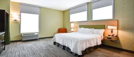 Una habitación de hotel con cama, una silla, un escritorio y una ventana.