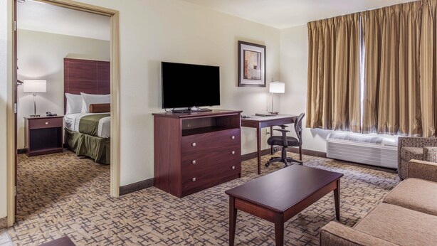 A hotel room with a bed, a desk, a television, a chair, and a sofa. - Cobblestone Hotel & Suites - Gering/Scottsbluff (Gering)