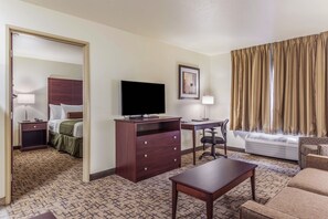 A hotel room with a bed, a desk, a television, a chair, and a sofa. - Cobblestone Hotel & Suites - Gering/Scottsbluff (Gering)