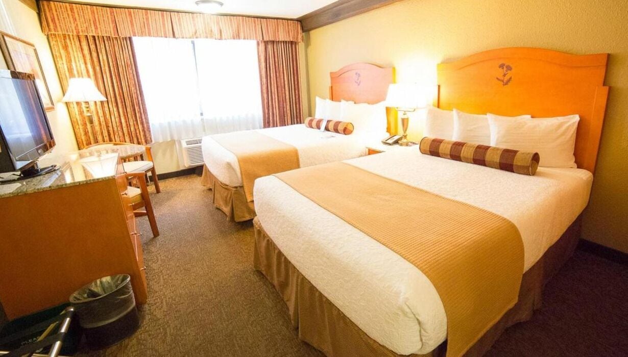 Habitación de hotel con dos camas, un escritorio con computadora, una silla y un televisor.