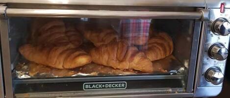 A BLACK+DECKER toaster oven with a glass door, containing several croissants.