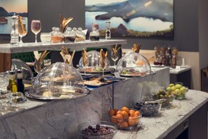 Un buffet con diversi cibi e bevande su un bancone in marmo.