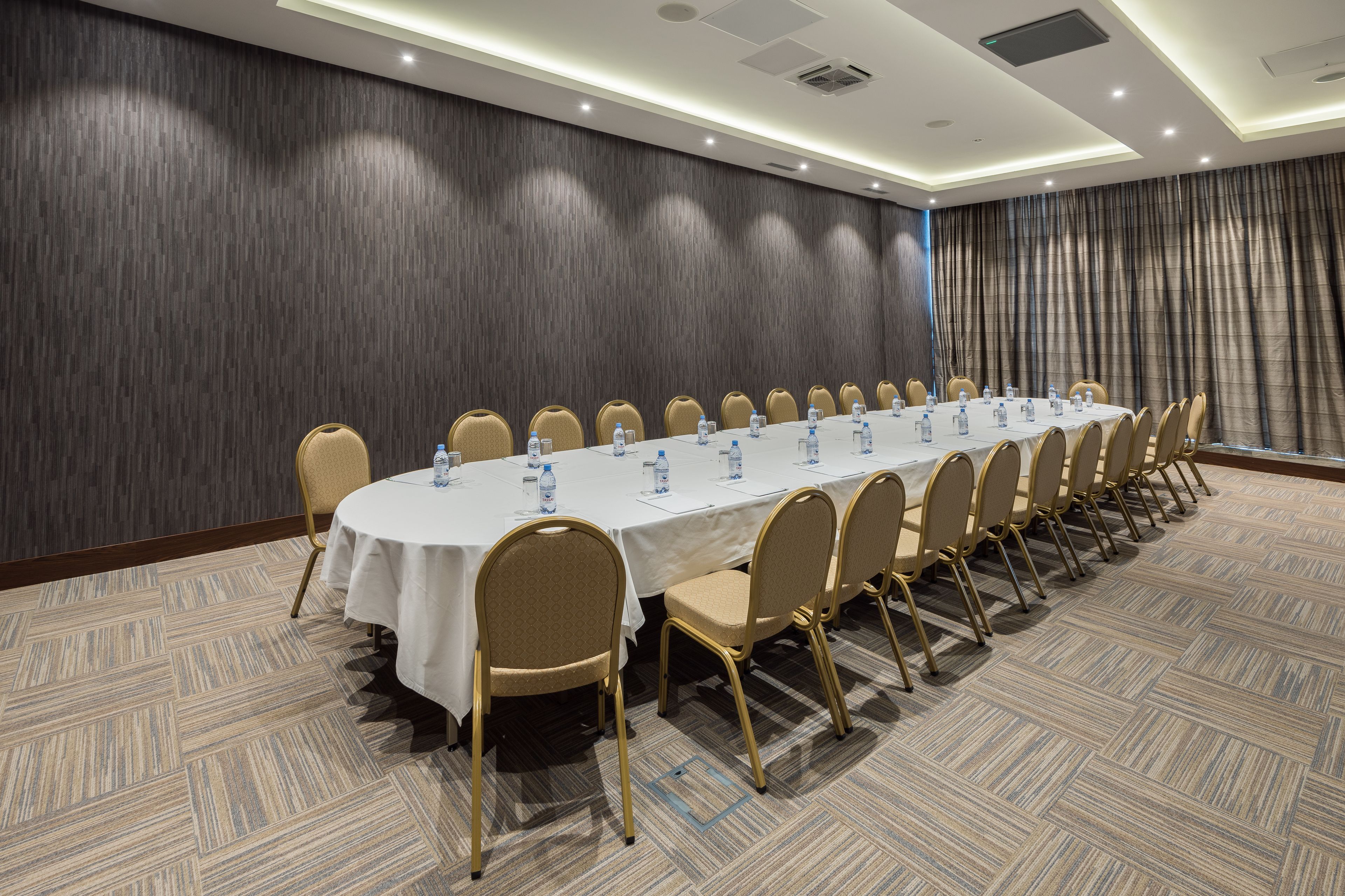 A conference room with a long table, chairs, and water bottles.