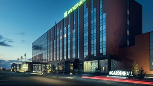 Ein modernes Hotel mit einem markanten "WYNDHAM GARDEN" Schild, großen Fenstern und einem gut beleuchteten Eingang.