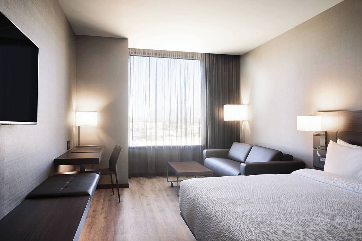 A hotel room with a bed, a sofa, a desk, and a chair.