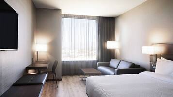 A hotel room with a bed, a sofa, a desk, and a chair.