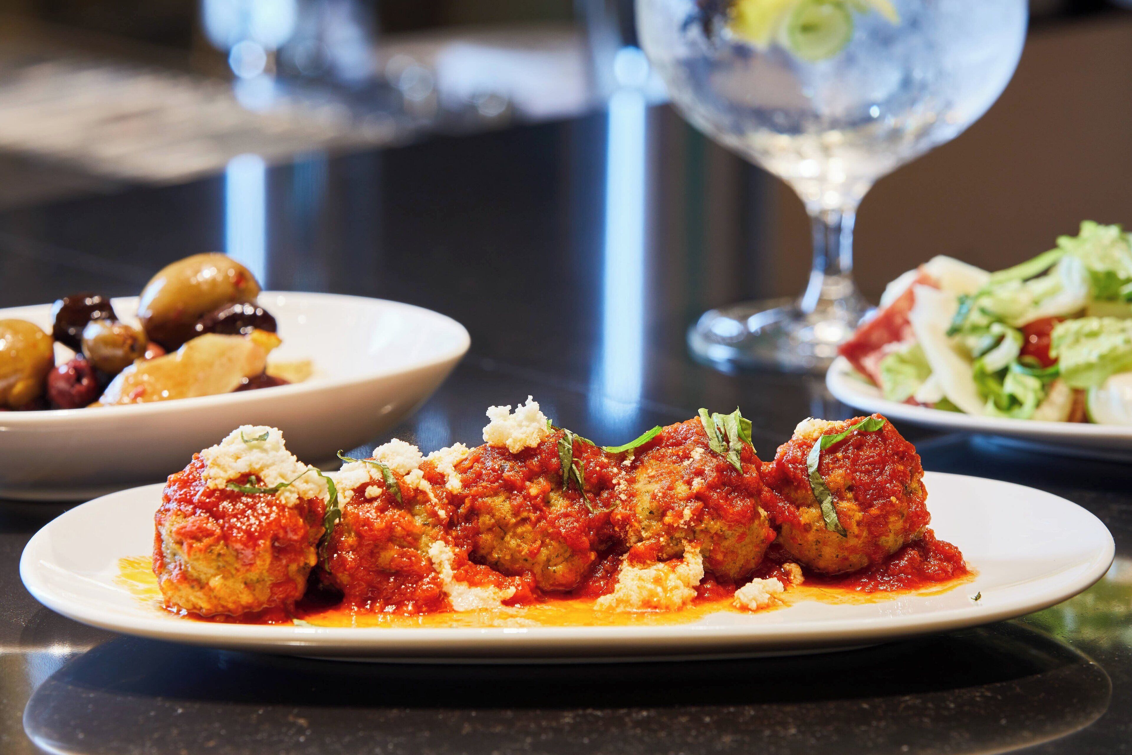 A plate of meatballs in tomato sauce with cheese on a table.