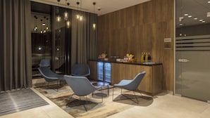 A modern interior with a bar area, seating, and a glass door leading to a balcony. - Courtyard by Marriott Edinburgh West (Edinburgh)