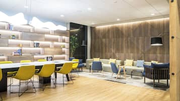Una sala de reuniones moderna con una mesa larga, sillas amarillas y un sofá con cojines azules y amarillos.