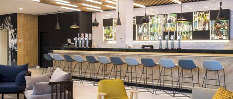 Eine moderne Bar mit einer langen Theke, mehreren Barhocker und hängenden Pendelleuchten.