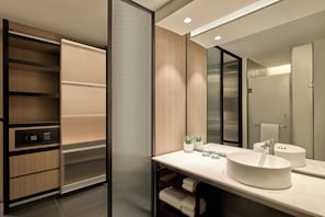 A modern bathroom with a large mirror, a round sink, and a built-in shower.