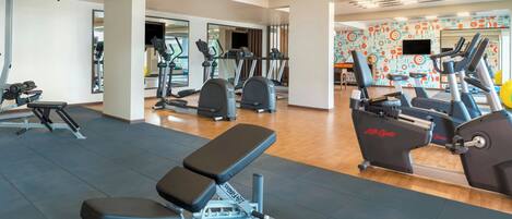 Un gimnasio moderno con diversos equipos de ejercicio, como cintas de correr, bicicletas estáticas y máquinas de pesas.