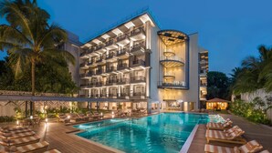 Ein Hotel mit Schwimmbad, mehreren Balkonen und Liegestühlen.