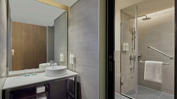 A modern bathroom with a glass-enclosed shower, a large mirror, and a white sink.
