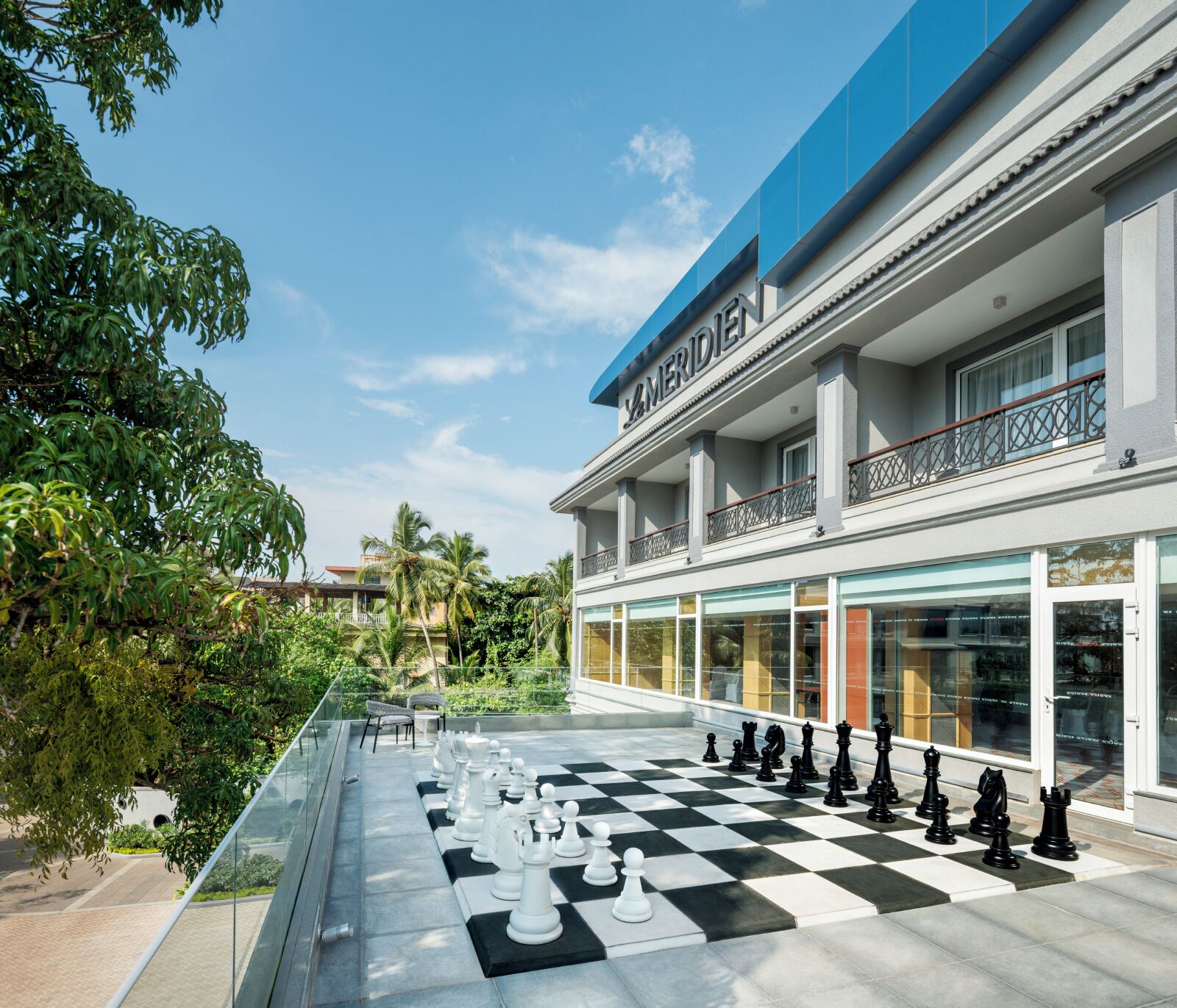 A chessboard set up on a balcony with a building in the background.