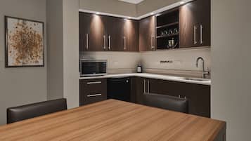 A modern kitchen with dark wood cabinets, a stainless steel microwave, a coffee maker, and a sink.