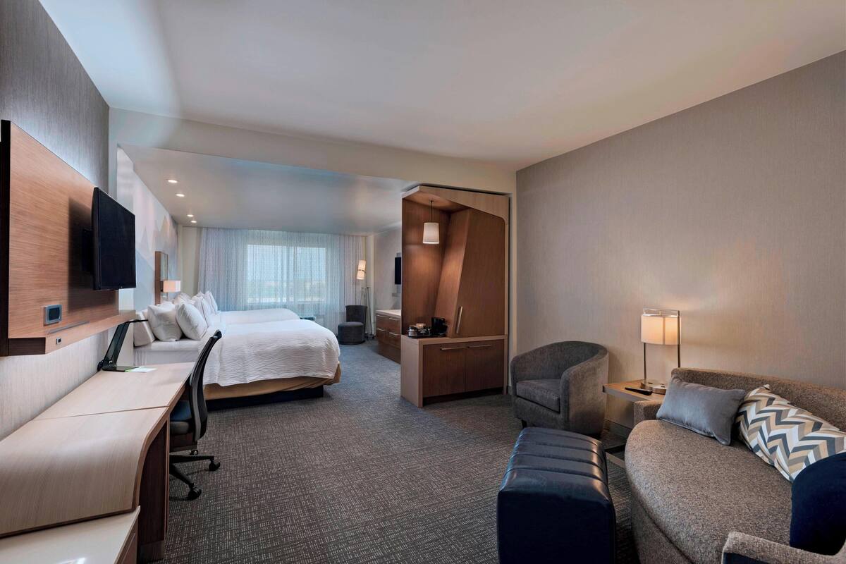 A hotel room with a bed, a desk, a sofa, a TV, and a wardrobe.