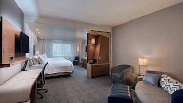 A hotel room with a bed, a desk, a sofa, a TV, and a wardrobe.