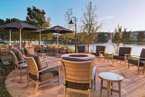 An outdoor patio with seating and umbrellas overlooking a body of water. - Courtyard by Marriott Houston Sugar Land/Lake Pointe (Sugar Land)