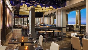 Een modern restaurant met een bar, hoge plafonds en uitzicht op de stad.