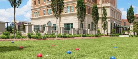 A grassy courtyard with a large brick building in the background.