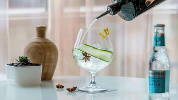 A glass with ice, cucumber slices, and star anise being filled with water from a bottle.