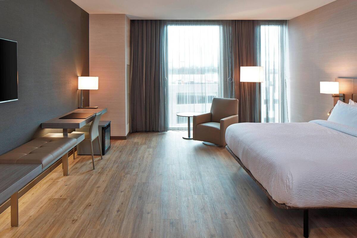 Una habitación de hotel con cama, escritorio, silla y televisor.