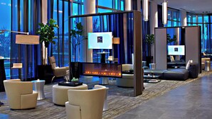 A modern lobby with a fireplace, comfortable seating, and large windows offering views of the cityscape. - AC Hotel by Marriott Columbus Dublin (Dublin)
