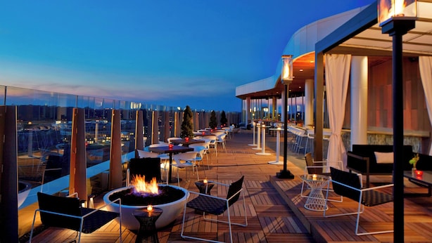 An outdoor terrace with a fire pit, seating, and a view of the cityscape at dusk. - AC Hotel by Marriott Columbus Dublin (Dublin)