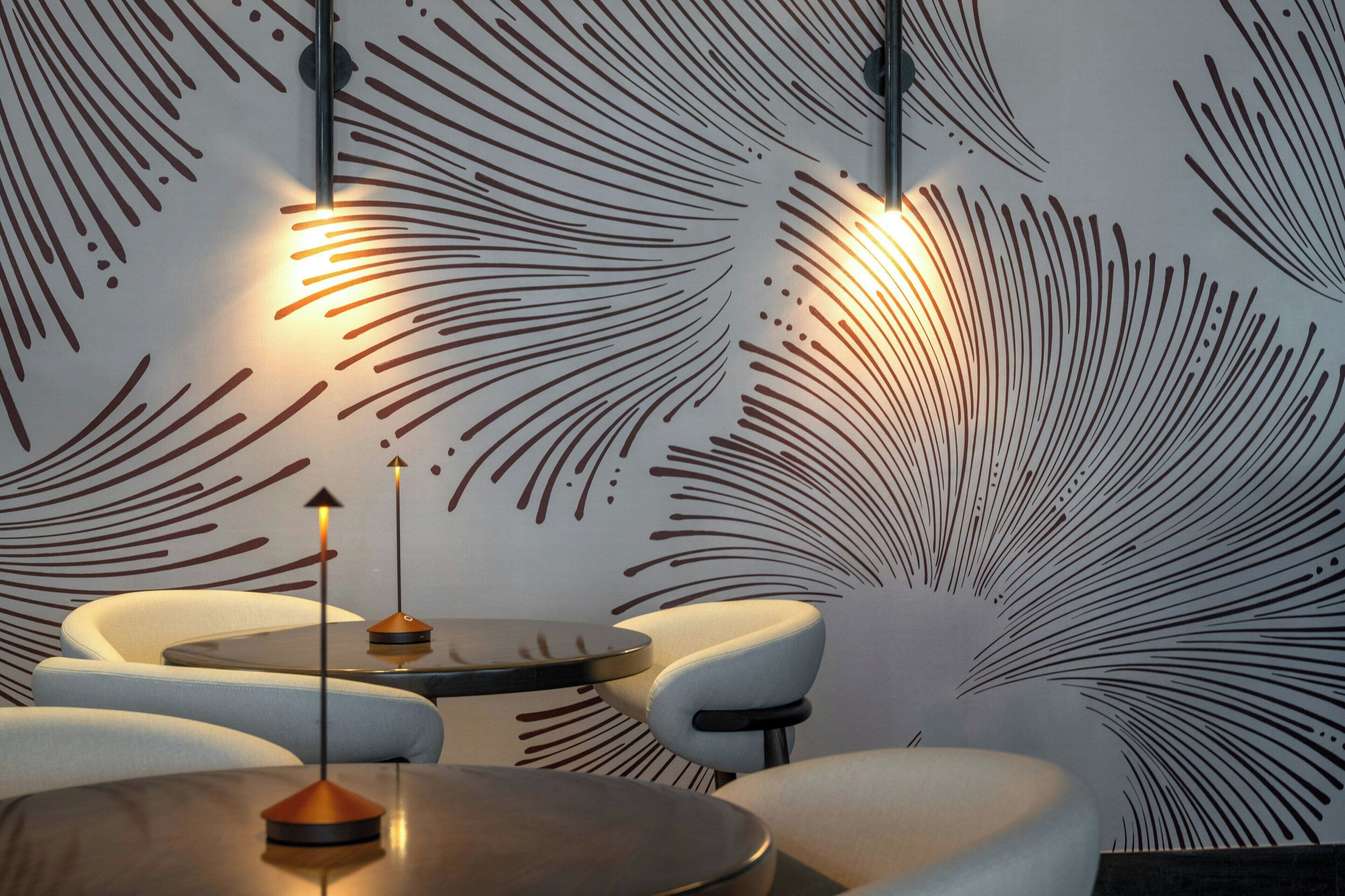 A modern interior with a patterned wall, a round table, and two chairs.