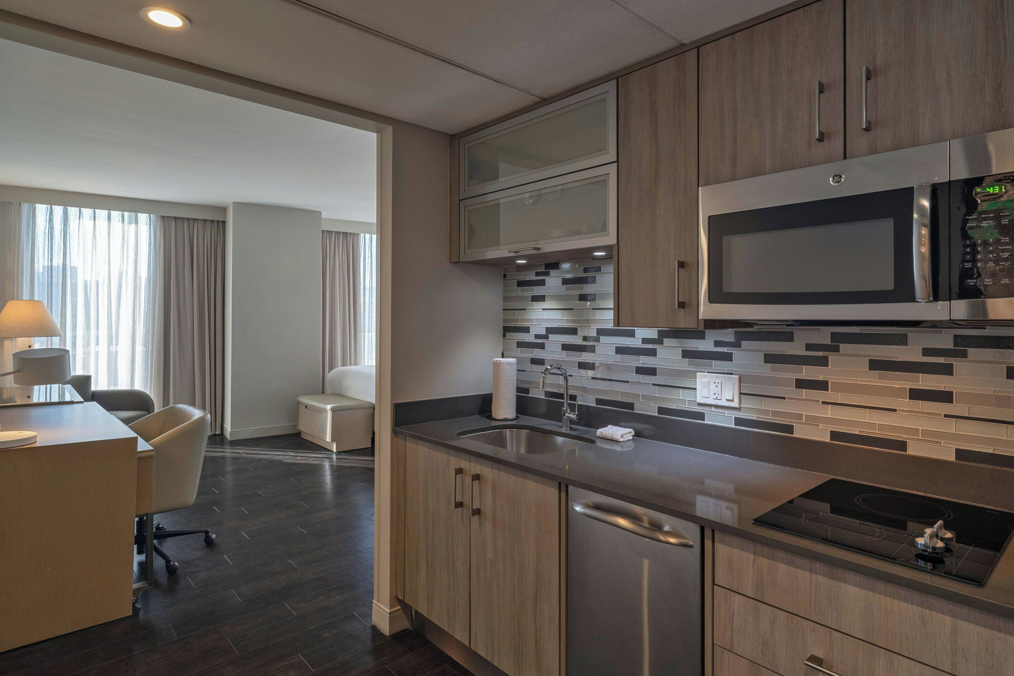 A modern kitchen with stainless steel appliances, a tiled backsplash, and wooden cabinets.