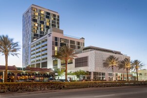 Un hotel moderno con varios pisos, un jardín cuidado y diversas opciones de restauración.
