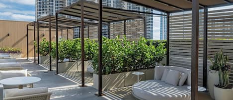 Terraza en la azotea con mobiliario exterior, una pérgola y vistas a edificios altos.