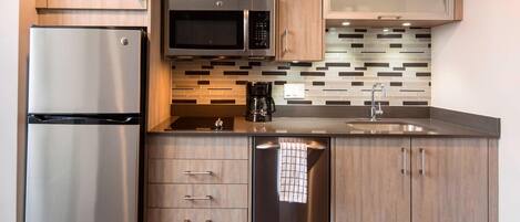 Una cocina moderna con electrodomésticos de acero inoxidable, armarios de madera y salpicadero de azulejos.