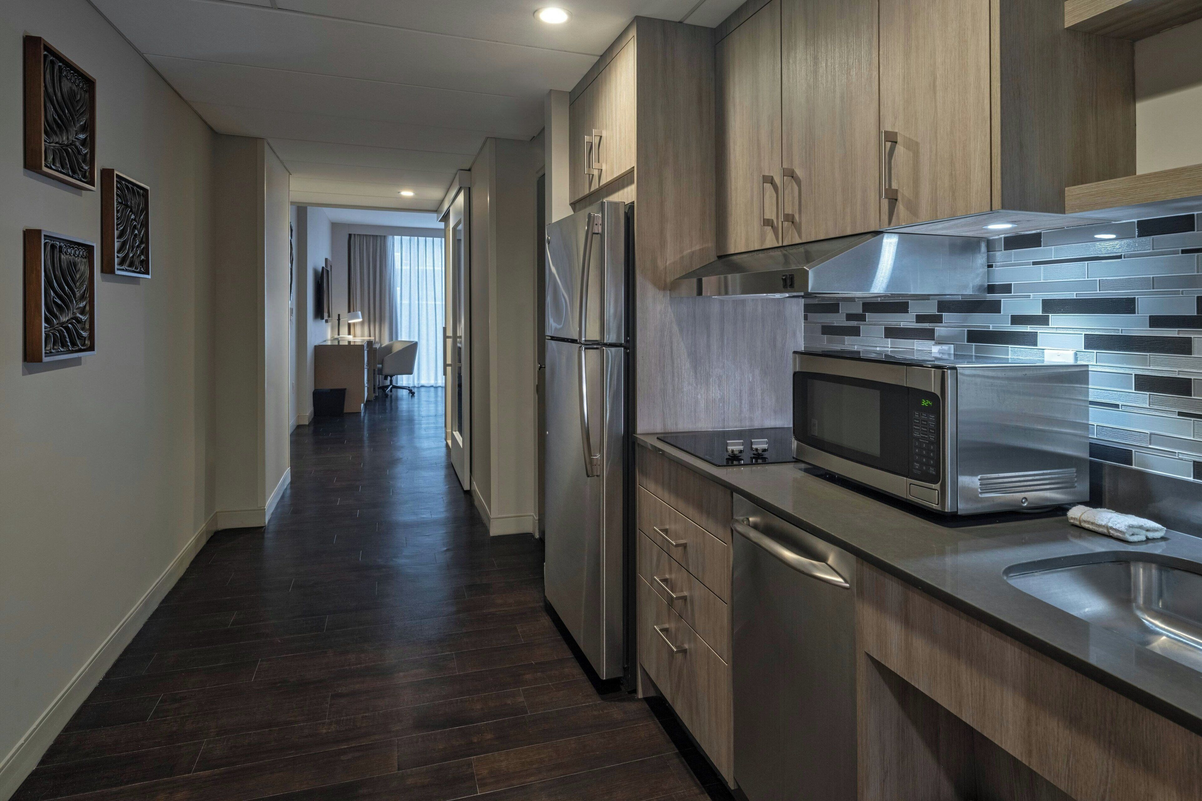 A modern kitchen with stainless steel appliances, wooden cabinets, and a tiled backsplash.