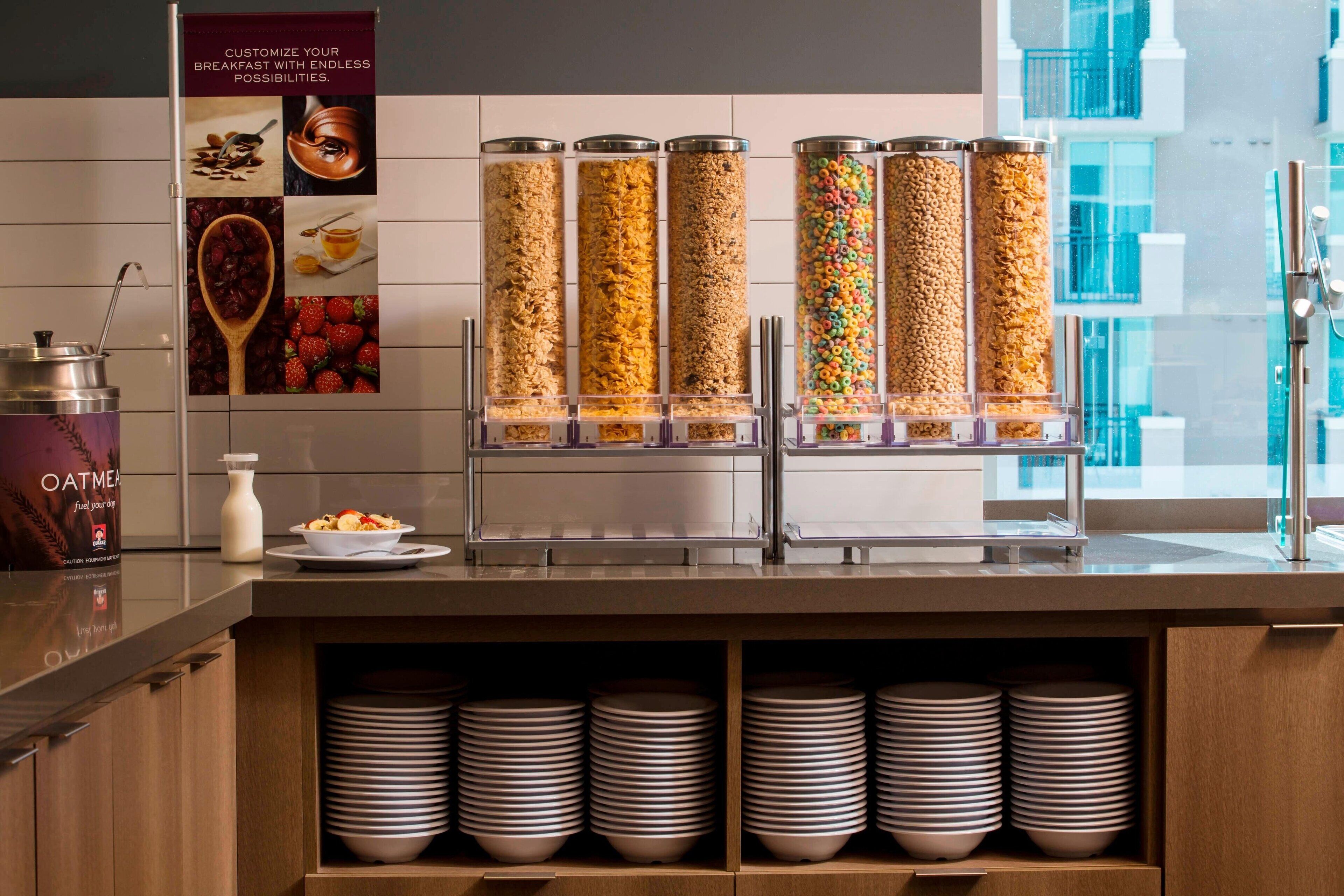 Una colazione a buffet con distributori automatici di cereali e un cartello che promuove la personalizzazione.