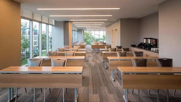 A conference room with long tables and chairs, large windows, and a coffee station.