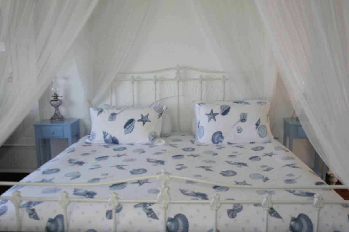 A bed with a canopy and a patterned bedspread.