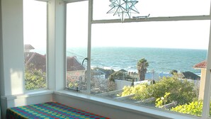 A room with a view of the sea through large windows, a colorful polka dot table, and a hanging star-shaped light fixture. - Blue On Blue Bed and Breakfast (Cape Town)