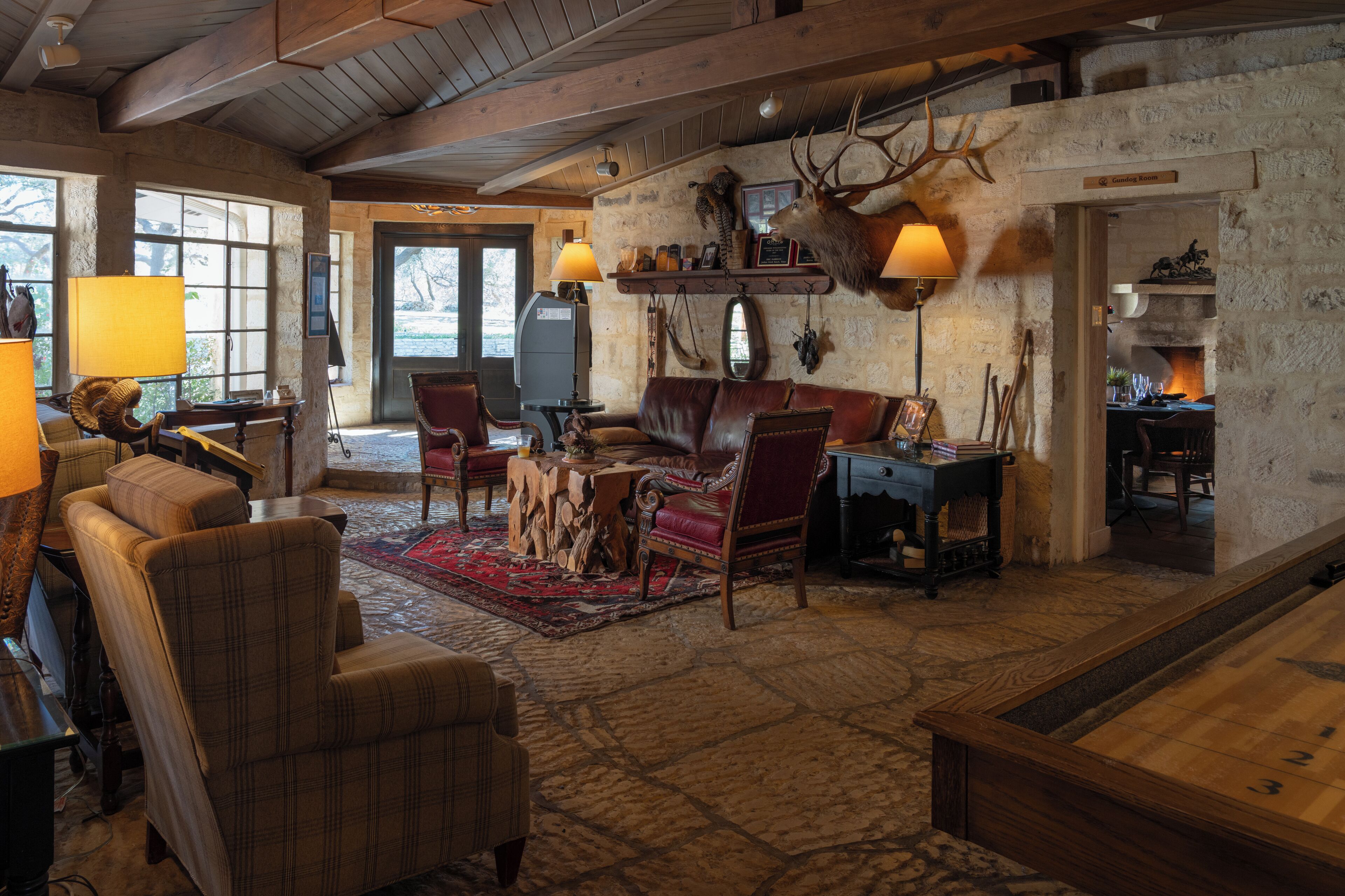 A rustic interior with a fireplace, leather furniture, and a mounted deer head.