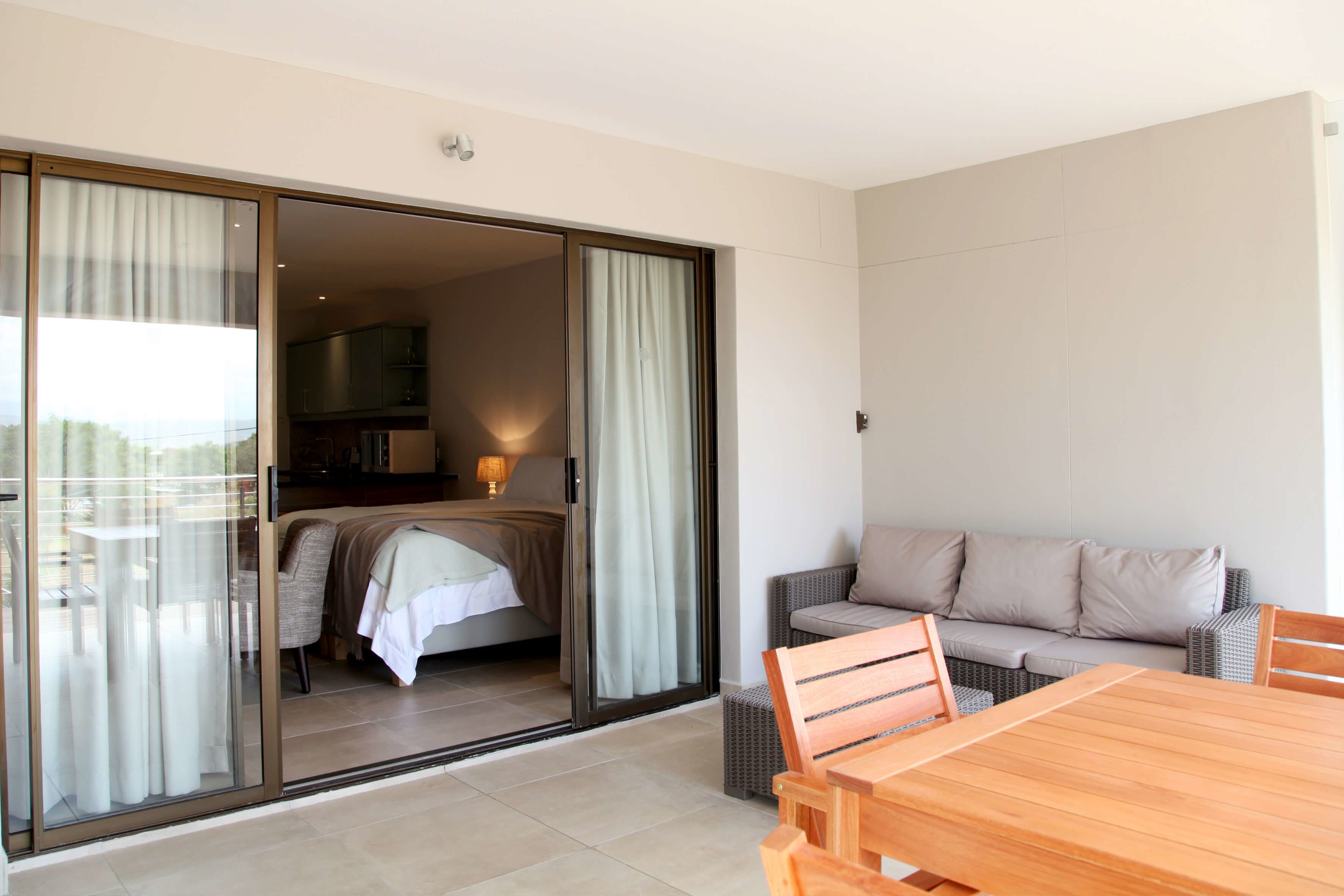 Een kamer met een bed, een slaapbank, een eettafel en een schuifpui naar een balkon.