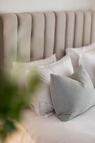 Una cama con cabecera y varias almohadas.