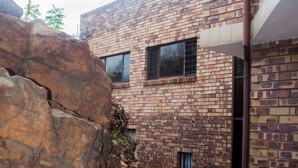 A brick building with a stone wall and a metal pipe.