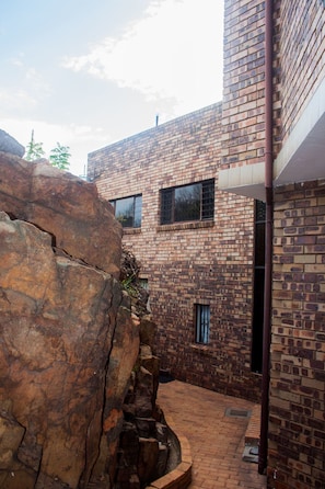 A brick building with a stone wall and a metal pipe. - Thabiso Guesthouse (Pretoria)