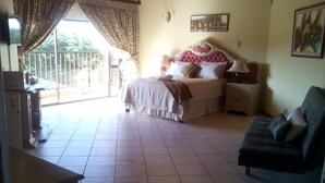 A bedroom with a bed, a nightstand, a sofa, and a TV.